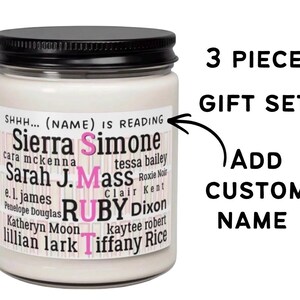 May include: A white candle in a clear glass jar with a black lid. The label features the text SHHH... (NAME) IS READING and a list of author names including Sierra Simone, Sarah J. Mass, and Tiffany Rice, with the word SMUT in pink letters.