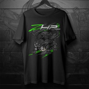 Può includere: T-shirt nero con un design stilizzato di moto e la scritta "ZH2" in verde e bianco. L'illustrazione della moto è principalmente nera e grigia con accenti verdi, su sfondo scuro.