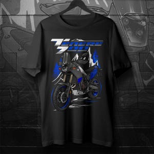 Könnte beinhalten: Schwarzes T-Shirt mit einem Motorrad-Motiv. Das Design zeigt den Text "TENERE 700" in Weiß und Blau, zusammen mit einer Illustration eines Motorrads mit blauen Akzenten und Bergformen.
