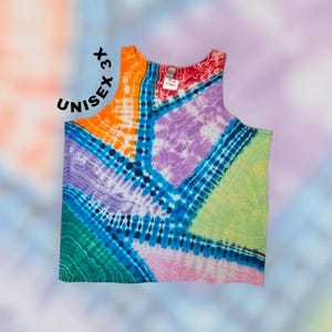 May include: A sleeveless tank top featuring a vibrant tie-dye pattern with geometric sections in orange, purple, light green, pink, and teal, separated by dark blue lines. The text UNISEX 3X is printed in black near the upper left shoulder area.