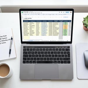 May include: A laptop displaying a spreadsheet titled "Client Roster" sits on a white desk, next to a notepad with a "To do List". A cup of coffee, a mouse, and a small potted succulent are also on the desk. The laptop is open.