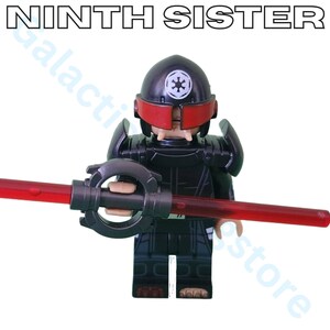 May include: A black action figure of the Ninth Sister, a Star Wars character. The figure has a black helmet with a red visor and holds a red lightsaber. The text "NINTH SISTER" is at the top.