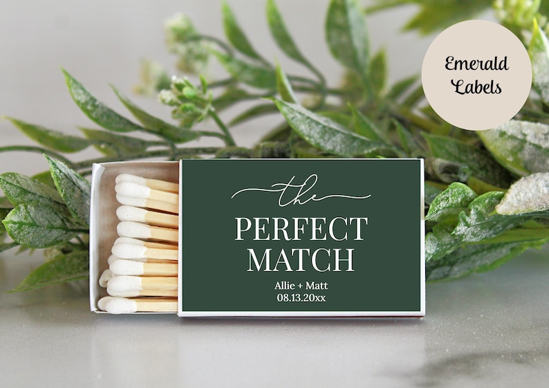 Peut inclure: Une bo&icirc;te d'allumettes rectangulaire avec une &eacute;tiquette vert fonc&eacute; portant le texte blanc "the PERFECT MATCH", les noms "Allie + Matt" et la date "08.13.20xx". La bo&icirc;te est entrouverte, r&eacute;v&eacute;lant une rang&eacute;e d'allumettes &agrave; bouts blancs.