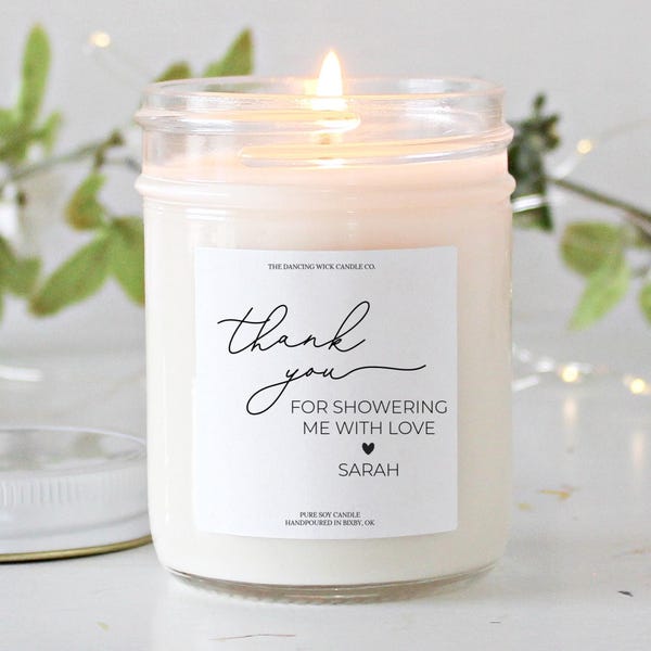 Puede incluir: Una vela de soja blanca en un tarro de vidrio transparente con una etiqueta blanca que dice "The Dancing Wick Candle Co." y "Gracias por llenarme de amor Sarah".
