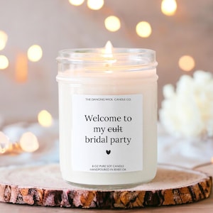 K&ouml;nnte beinhalten: Eine wei&szlig;e Sojawachskerze mit einem Etikett, auf dem "The Dancing Wick Candle Co. Welcome to my eult bridal party" und "8 oz pure soy candle handpoured in Bixby, OK" steht.