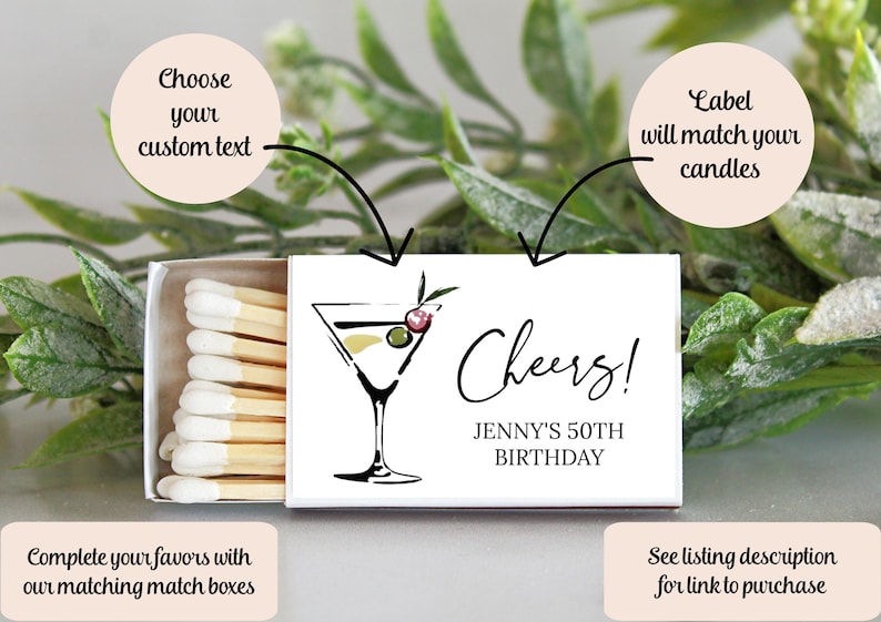 K&ouml;nnte beinhalten: Eine wei&szlig;e Streichholzschachtel mit einer Martini-Illustration und dem Text "Cheers!" und "Jenny's 50th Birthday." Die Streichholzschachtel enth&auml;lt auch den Text "W&auml;hlen Sie Ihren individuellen Text" und "Das Etikett passt zu Ihren Kerzen."