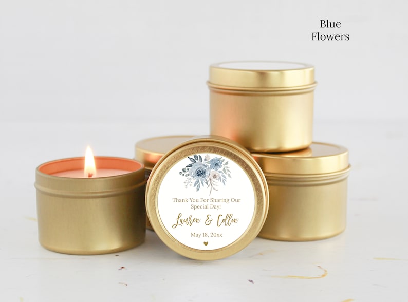 May include: A group of round gold metal candle tins, one of which is lit with a visible flame. A circular white label on the front features a blue floral illustration, the text "Thank You For Sharing Our Special Day!", "Lauren & Collin", and "May 18, 20xx".