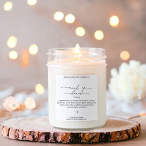 May include: A white candle in a clear glass jar with a label that reads "maid of honor noun best friend or sister, therapist, party planner, train fixer, bathroom assistant, someone the wedding would feel incomplete without PURE SOY CANDLE HANDPOURED IN BIXBY, OK"