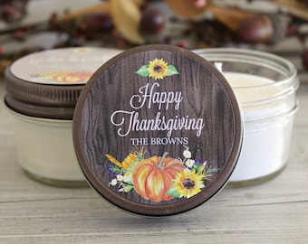 May include: A brown and white candle jar with a woodgrain design and a label that says "Happy Thanksgiving The Browns". The label also features a pumpkin, sunflowers, and other fall foliage.