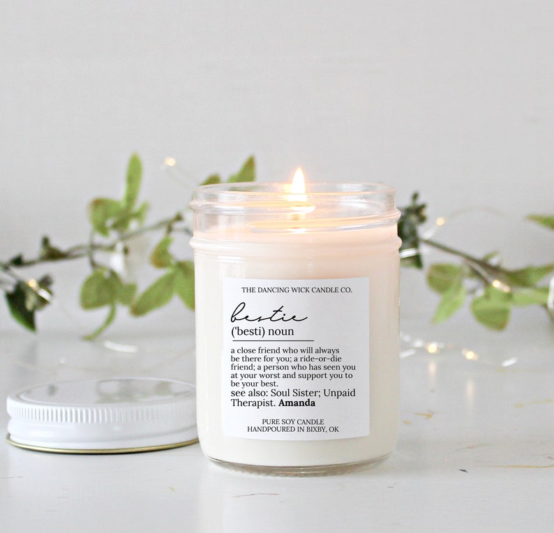 May include: A clear glass jar candle with a white label that reads "THE DANCING WICK CANDLE CO. bestie ('besti) noun a close friend who will always be there for you; a ride-or-die friend; a person who has seen you at your worst and support you to be your best. see also: Soul Sister; Unpaid Therapist. Amanda PURE SOY CANDLE HANDPOURED IN BIXBY, OK"