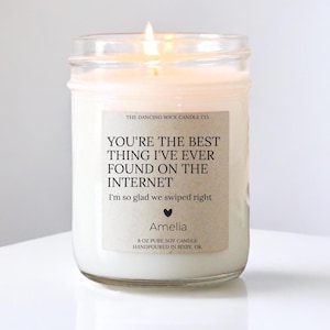 May include: A white soy candle in a glass jar with a brown label that reads "You're the best thing I've ever found on the internet. I'm so glad we swiped right. Amelia. 8 oz pure soy candle. Handpoured in Bixby, OK."