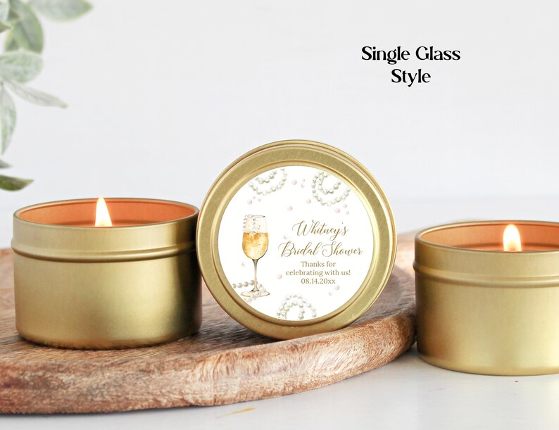 May include: Gold candle tin with a white label that says "Whitney's Bridal Shower" with a champagne glass graphic. The label also includes the text "Thanks for celebrating with us! 08.14.20xx."