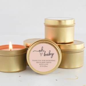 May include: Gold candle tins with a pink label that says "oh baby" with a heart. The label also says "Thank you for showering Erin & Baby Smith with love 07.25.20xx".