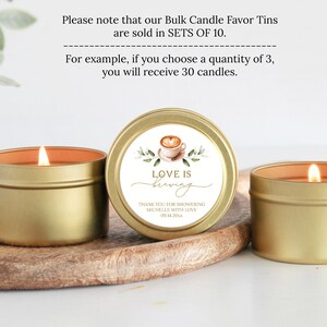 May include: Three gold candle tins with a white label that says "Love is Brewing". The label also includes a watercolor illustration of a coffee cup and green leaves. The text "Thank you for showering Michelle with love 09.14.20" is also on the label.