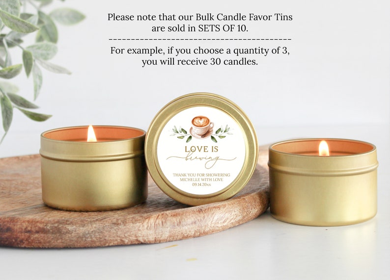 May include: Three gold candle tins with a white label that says "Love is Brewing". The label also includes a watercolor illustration of a coffee cup and green leaves. The text "Thank you for showering Michelle with love 09.14.20" is also on the label.