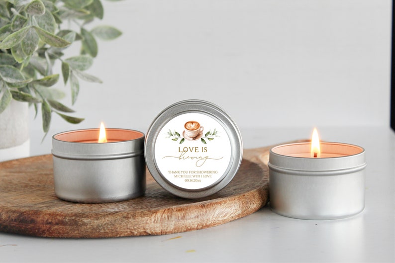 May include: Three silver candle tins with a white label on one tin. The label has a watercolor illustration of a coffee cup with a heart design and the text "Love is brewing". The text below the illustration says "Thank you for showering Michelle with love on her wedding day."