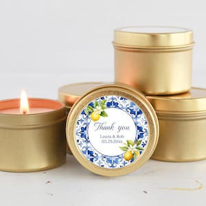 May include: Gold candle tins with a blue and white floral design label. The label says "Thank you Laura & Rob 03.29.20xx".