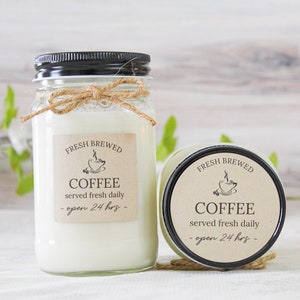 May include: Two glass jars with black lids and brown paper labels. The labels say "Fresh Brewed Coffee served fresh daily - open 24 hrs -" with a small illustration of a coffee cup.