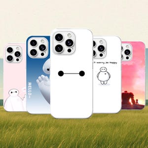 Può includere: Cinque cover per smartphone con disegni di Baymax. Una è rosa con Baymax, una blu con 'HELLO~' e Baymax, una bianca con il volto di Baymax, una bianca con Baymax e 'Don't worry, be happy.', e una mostra una scena al tramonto con personaggi.