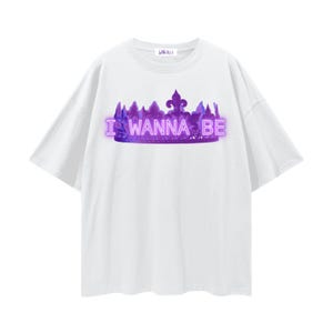 May include: White t-shirt with a purple crown design and the text "I WANNA BE" in a neon-style font. The shirt has short sleeves and a crew neck.