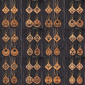 Puede incluir: Una colección de treinta y seis pares de pendientes de madera de color marrón claro con intrincados patrones geométricos y circulares cortados con láser. Cada par cuenta con ganchos de metal y muestra una variedad de diseños simétricos.