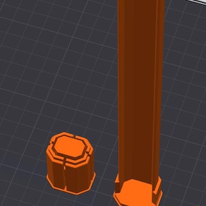 May include: Two orange, geometric 3D-printed objects. One is a tall, rectangular prism with an octagonal base and top. The other is a shorter, octagonal prism. Both objects are on a dark gray surface with a grid pattern.