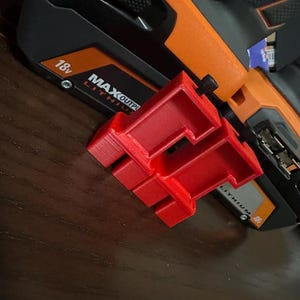 May include: A bright red 3D-printed tool attachment is positioned next to a black and orange power tool. The power tool has the text "MAX OUTPUT" and "18v" printed on it. The attachment has a unique, geometric design.