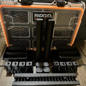 May include: A black and orange Ridgid Pro System tool box with various black storage components. The clear lid allows visibility of the contents. The tool box is open, displaying several black storage containers, dividers, and mounting pieces.