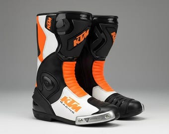 Botas de moto de competición KTM, botas de moto de cuero negro y naranja, equipamiento de protección para motos deportivas.