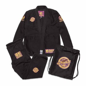 Puede incluir: Un conjunto de uniforme de artes marciales negro, que incluye una chaqueta, pantalones y una bolsa con cordón. La chaqueta y los pantalones tienen parches con logotipos dorados y morados. La bolsa también presenta un logotipo a juego. El conjunto está diseñado para el entrenamiento de artes marciales.