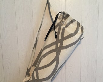 May include: A white yoga mat bag with a gray abstract pattern and a black drawstring. The bag has a long black strap for carrying over the shoulder.