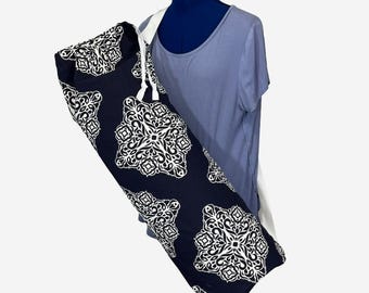 May include: A navy blue yoga mat bag with a white geometric pattern. The bag has a white drawstring closure and a white shoulder strap. The bag is displayed on a mannequin wearing a blue t-shirt.