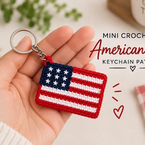 Pode incluir: Um porta-chaves retangular de croché com o design da bandeira americana, apresentando um cantão azul com nove estrelas brancas e riscas horizontais vermelhas e brancas. Inclui um anel de metal prateado e mede 5-6 cm.