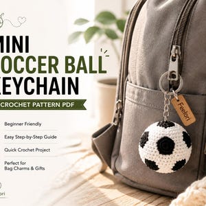 Peut inclure: Un porte-clés en forme de ballon de football crocheté en noir et blanc, accroché à un sac à dos gris. Le porte-clés a une petite étiquette en bois avec le nom "Feelori". Le texte "Mini Soccer Ball Keychain Crochet Pattern PDF" est également visible.