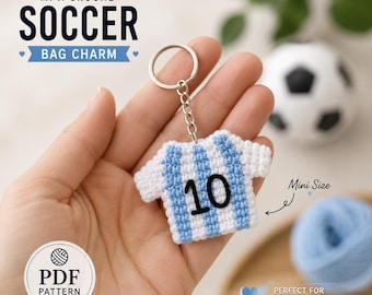 May include: A crocheted soccer jersey bag charm featuring vertical light blue and white stripes with the number 10 stitched in black on the front. The charm is attached to a silver-toned metal split ring by a short chain link.