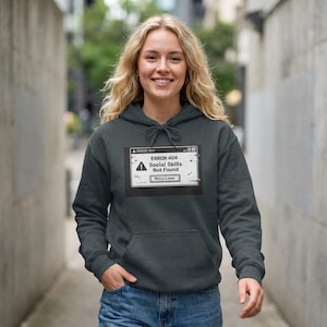 May include: Dark grey hoodie with a front pocket and a drawstring hood. The hoodie displays a graphic resembling an error message, stating "ERROR 404 Social Skills Not Found" in a white box with a warning symbol and "Retry Later".