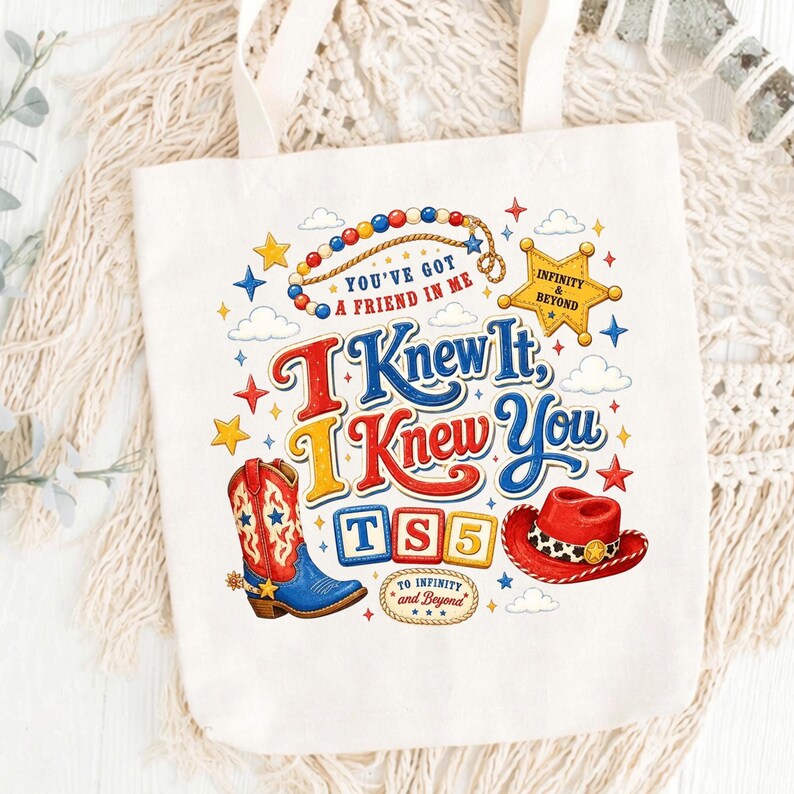 Puede incluir: Una bolsa de tela blanca con un estampado gr&aacute;fico colorido que muestra una bota de vaquero roja y azul, un sombrero de vaquero rojo, una estrella de sheriff amarilla y bloques de construcci&oacute;n que forman TS5. El texto dice You've Got A Friend In Me, I Knew It, I Knew You y To Infinity and Beyond.
