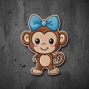 May include: An embroidered patch featuring a brown monkey with a light tan face, belly, and hands. The monkey has large ears, a small smile, pink cheeks, and a bright blue bow tied at the top of its head. The design has a thick white border.