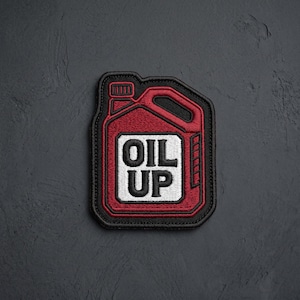 May include: An embroidered patch shaped like a motor oil jug with a red body, black border, and a white central square containing the black text OIL UP. The design features a handle and a cap, rendered in detailed thread work on a dark surface.