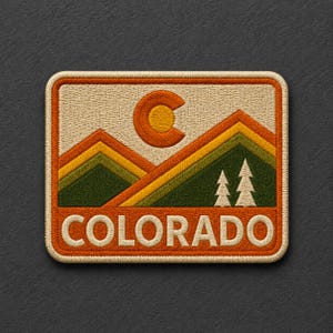 May include: A rectangular embroidered patch featuring a mountain landscape with layered green, yellow, and orange peaks, a yellow sun symbol, and two white pine trees. The word COLORADO is stitched in white capital letters at the bottom.