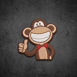 May include: An embroidered patch featuring a cartoon monkey with brown fur, a large white smiling mouth, and a small red bowtie. The monkey is depicted from the chest up, gesturing with a thumbs-up sign using its right hand against a dark background.