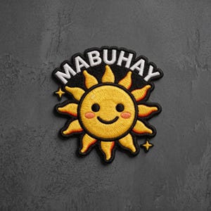 May include: An embroidered patch featuring a yellow sun with a smiling face, pink cheeks, and black eyes. The sun is set against a black background with the white text MABUHAY arched above it. Two small four-pointed yellow stars flank the sun design.