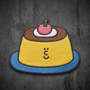 May include: An embroidered patch featuring a yellow custard dessert on a blue plate. The dessert has a brown top, a white dollop of cream, and a pink cherry. A simple black line face with two dots for eyes and a curved mouth is centered on the yellow base.