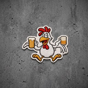 May include: An embroidered patch featuring a white cartoon chicken with a red comb and wattle, holding a yellow beer mug in each wing. The chicken has a wide, smiling expression with closed eyes, and the design is outlined in white thread.