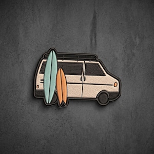 May include: An embroidered patch featuring a cream-colored van with a black roof rack. Two surfboards are attached to the side, one light blue and one orange. The design is outlined in black thread, showcasing a side profile of the vehicle.