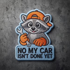 May include: An embroidered patch featuring a gray raccoon wearing an orange baseball cap and holding a silver wrench. The patch has a light blue border and includes the black text NO MY CAR ISN'T DONE YET printed on the lower section.