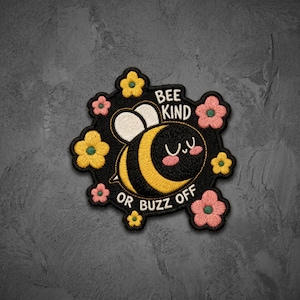 May include: An embroidered patch featuring a cartoon bee with yellow and black stripes, white wings, and pink cheeks. The text reads BEE KIND OR BUZZ OFF. The design is surrounded by small yellow and pink flowers on a black background.