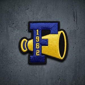 May include: An embroidered patch featuring a large blue letter F with a yellow megaphone integrated into the design. The vertical bar of the letter F contains the yellow numbers 1962 stacked vertically. The entire patch has a black border.