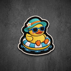 May include: An embroidered patch featuring a yellow duck wearing blue sunglasses and a teal sun hat with a white flower. The duck is sitting in a blue and white striped inflatable pool float, surrounded by blue water, all outlined in black.