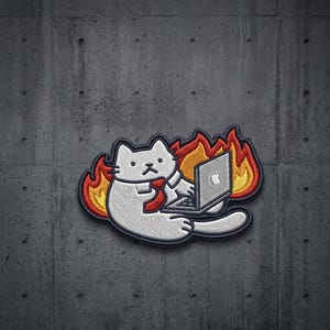 May include: An embroidered patch featuring a white cat wearing a red necktie, sitting in front of a laptop computer while surrounded by orange and red flames. The cat has a neutral expression and is positioned against a dark gray background.
